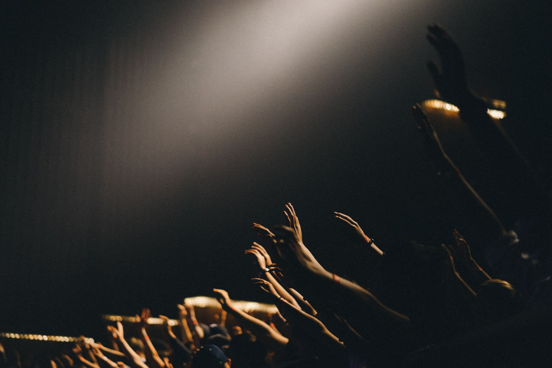 Hands raised in worship under a shaft of light